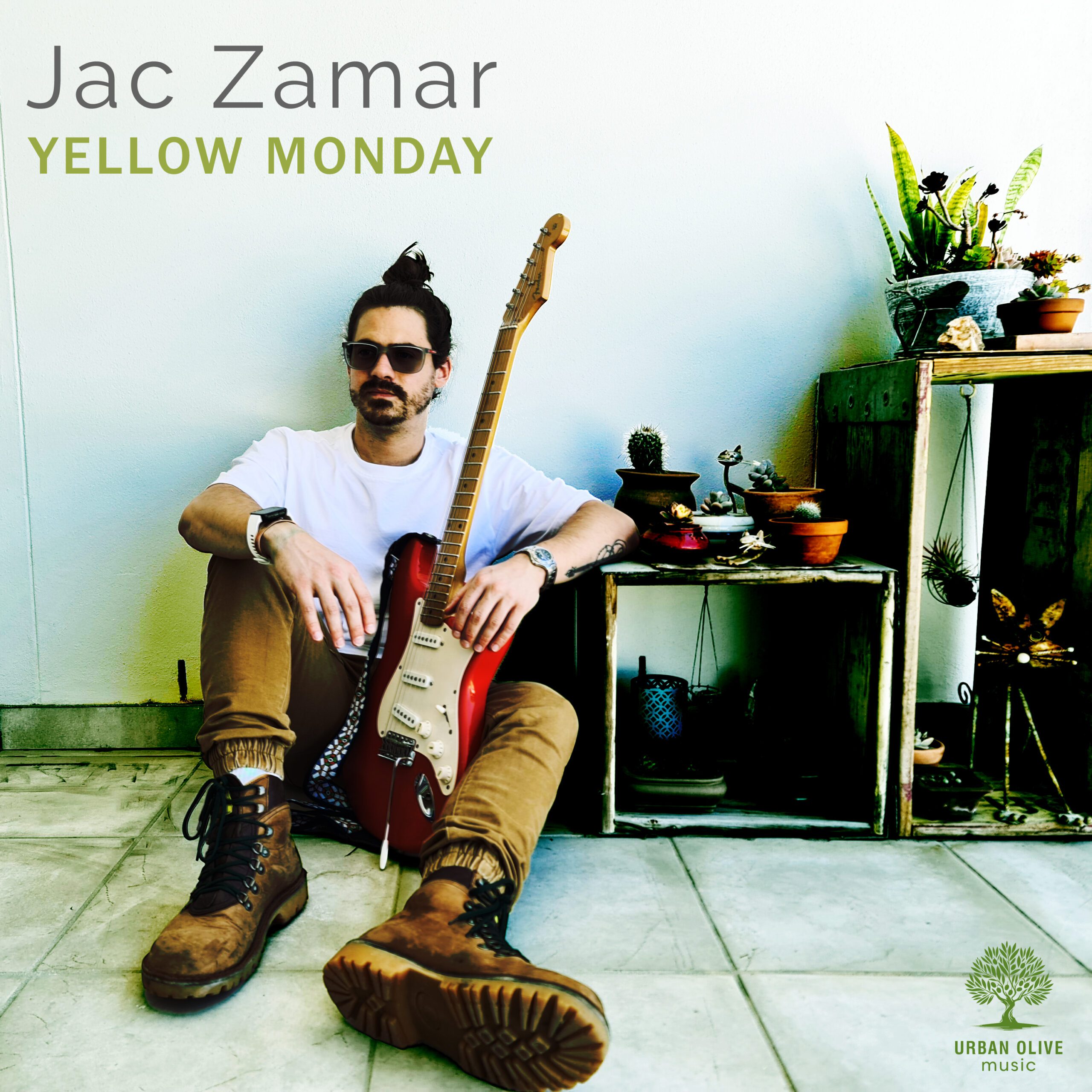 Yellow Monday — single artwork: Jac Zamar seated with a red Fender Stratocaster guitar among potted plants